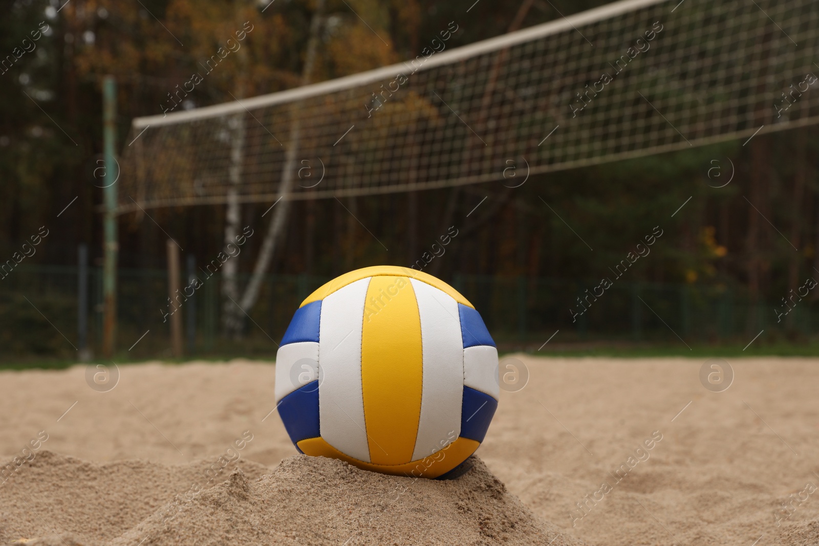 Photo of Colorful volleyball ball on sand court, closeup