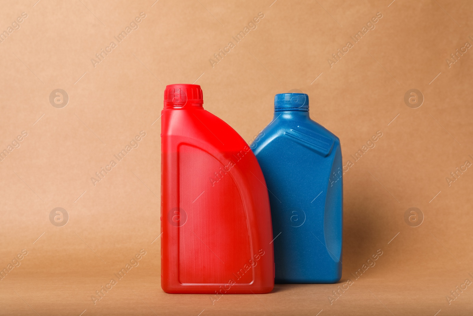 Photo of Motor oil in different canisters on light brown background