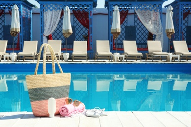 Photo of Beach accessories on wooden deck near swimming pool. Space for text