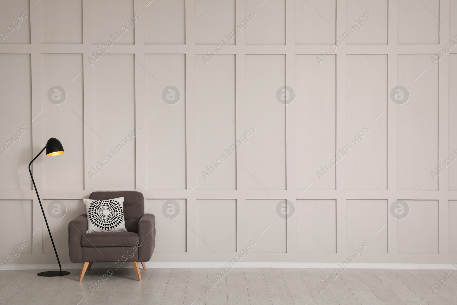 Photo of Grey armchair and lamp near empty molding wall indoors, space for text