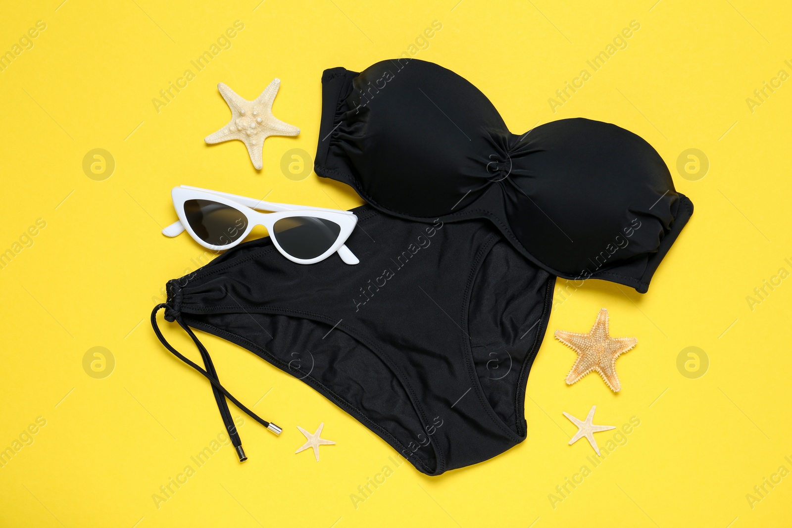 Photo of Woman's stylish bikini and sunglasses on yellow background, flat lay