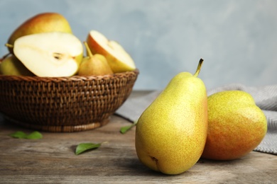 Ripe juicy pears on brown wooden table against blue background