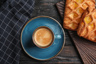 Delicious coffee and pastries on black wooden table, flat lay