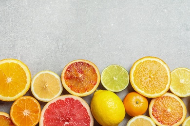 Photo of Different citrus fruits on grey background, flat lay. Space for text