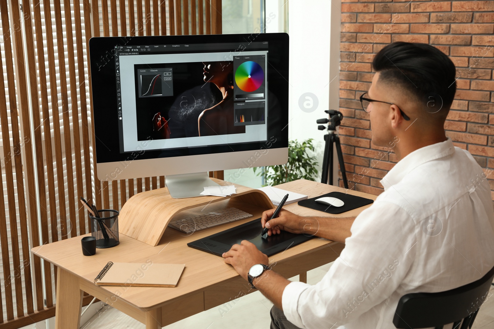 Photo of Professional retoucher working on graphic tablet at desk in office