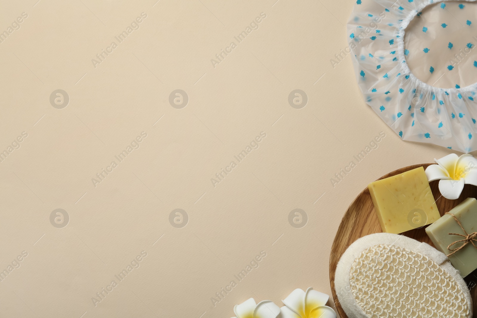 Photo of Flat lay composition with shower cap and toiletries on beige background. Space for text