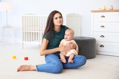 Photo of Young mother suffering from postnatal depression and cute baby girl at home