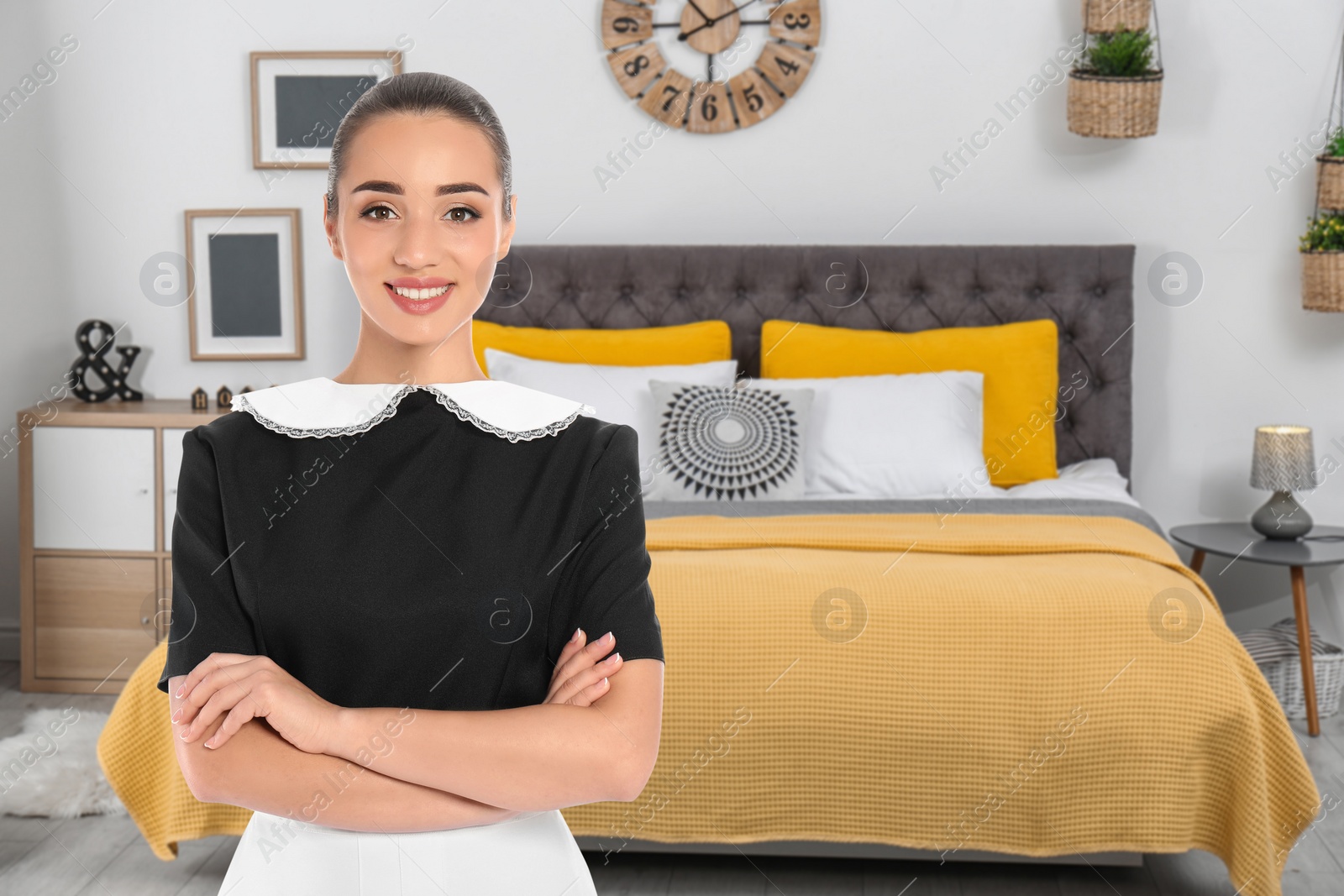 Image of Beautiful chambermaid near bed in hotel room