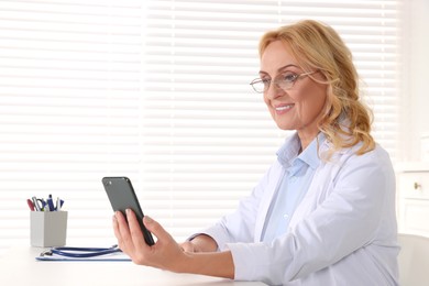 Photo of Doctor with glasses and smartphone consulting patient in clinic. Online medicine concept