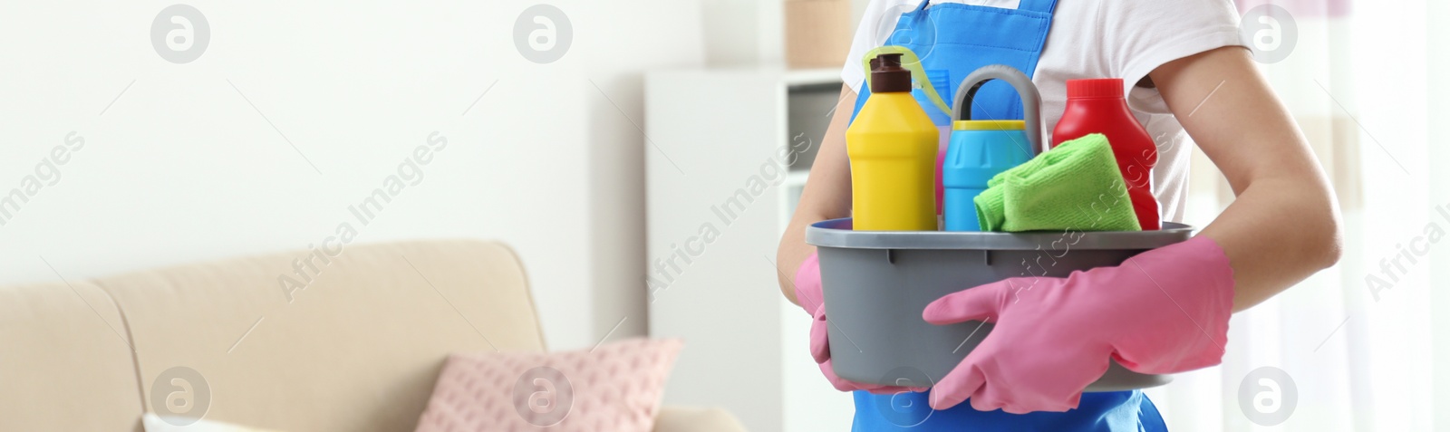 Image of Closeup view of woman with detergents in living room, banner design with space for text. Cleaning service