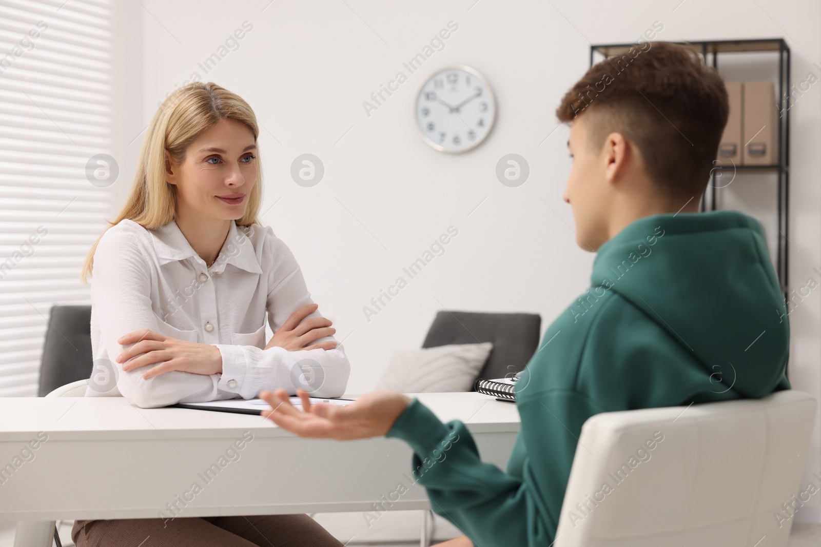 Photo of Psychologist working with teenage boy at table in office