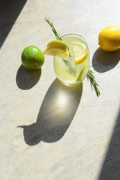 Photo of Tasty refreshing lemonade and ingredients on light grey table, space for text. Summer drink