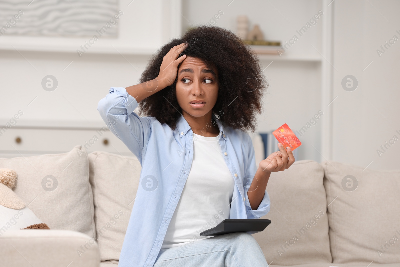 Photo of Confused woman with calculator and credit card planning budget at home. Debt problem