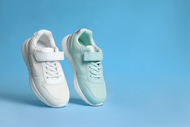 Photo of Two stylish sneakers on light blue background. Space for text