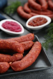 Photo of Tasty sausages served on black table, closeup. Meat product