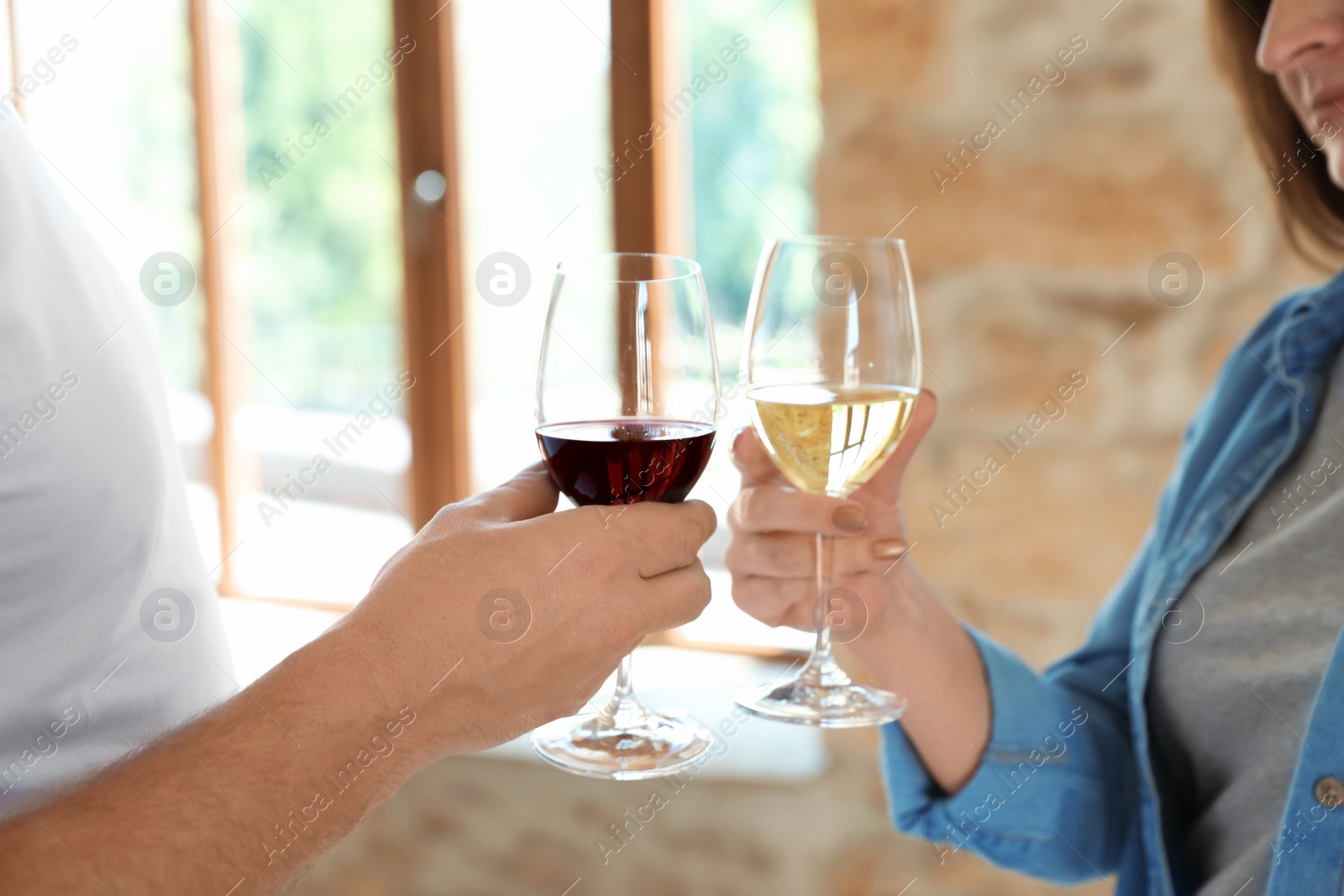 Photo of Couple with glasses of white and red wines indoors, closeup