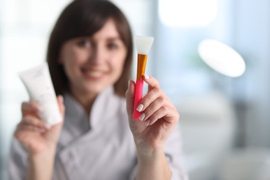 Photo of Cosmetologist with silicone brush and cosmetic product in clinic, selective focus