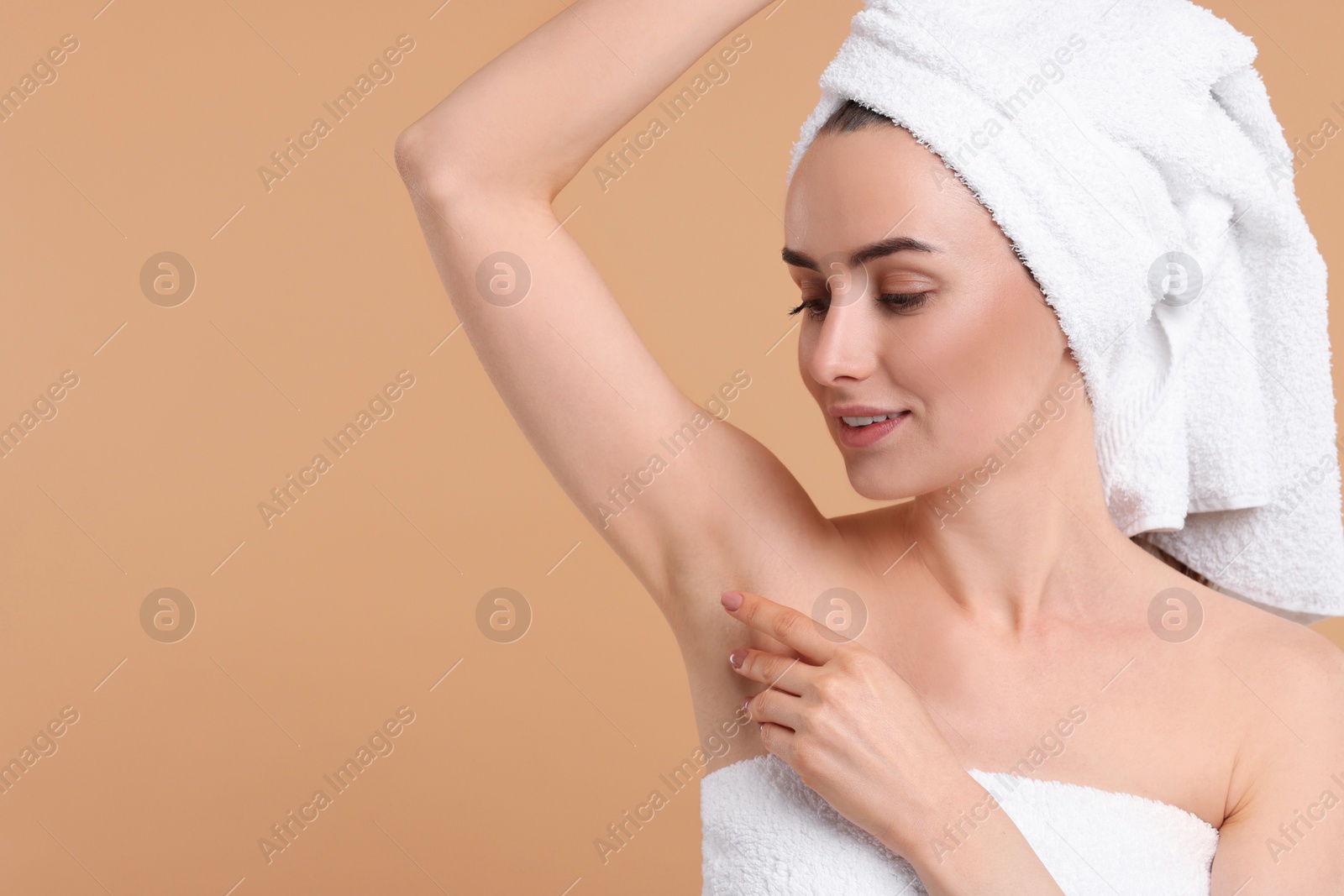 Photo of Beautiful woman showing armpit with smooth clean skin on beige background, space for text