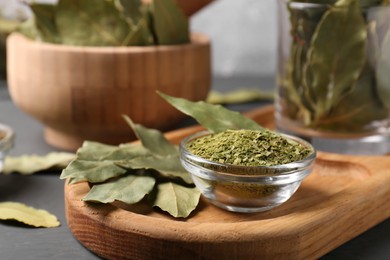 Photo of Whole and ground bay leaves on grey table, closeup