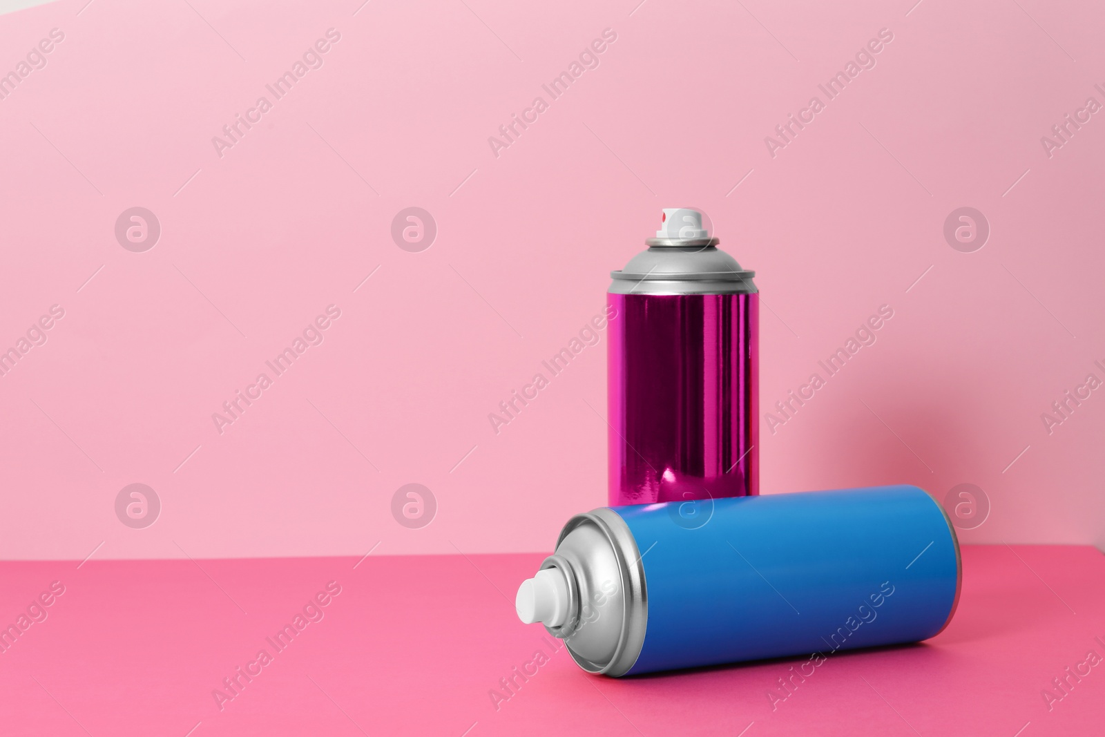 Photo of Cans of different spray paints on color background. Space for text