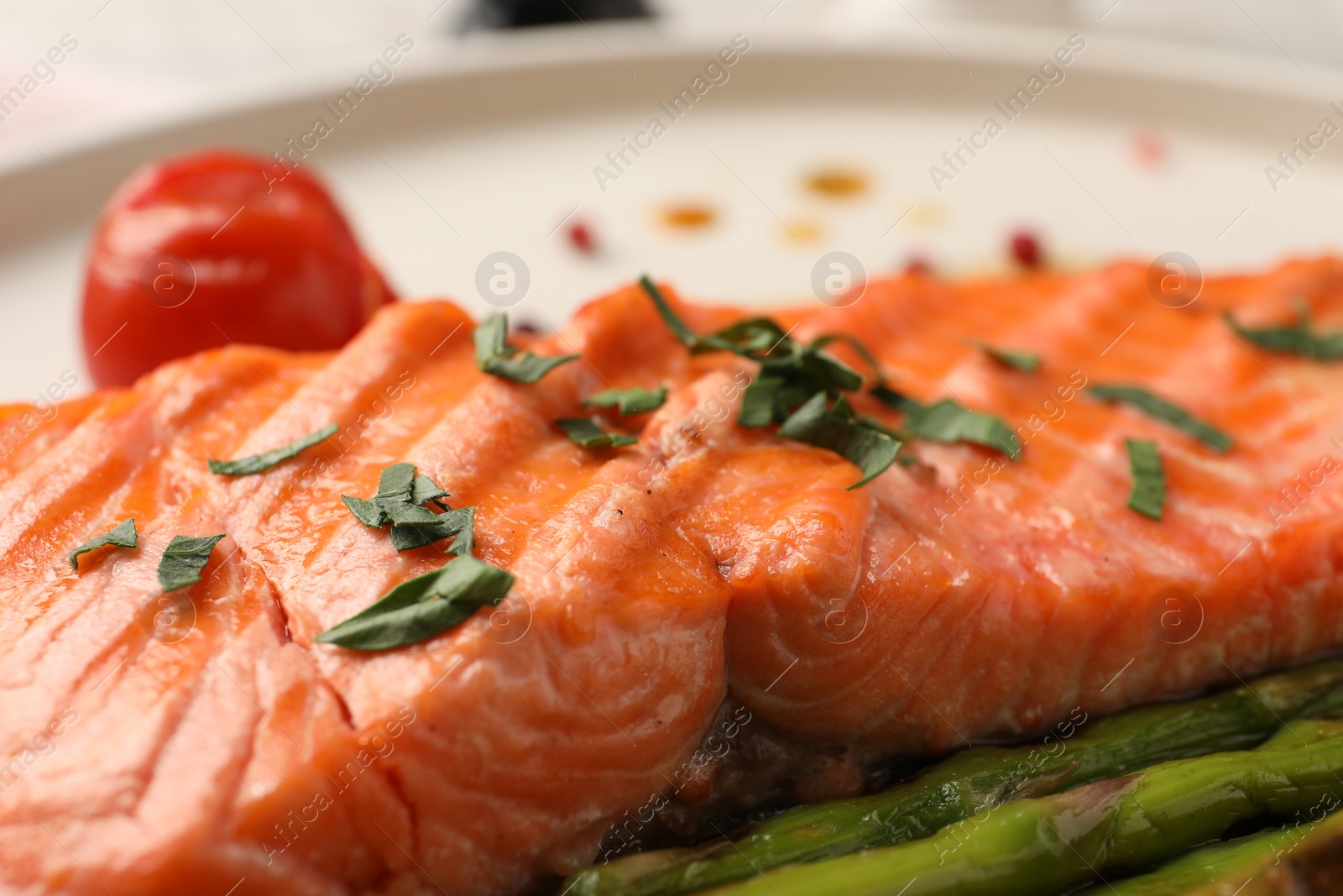 Photo of Tasty grilled salmon with tomato and spices on plate, closeup