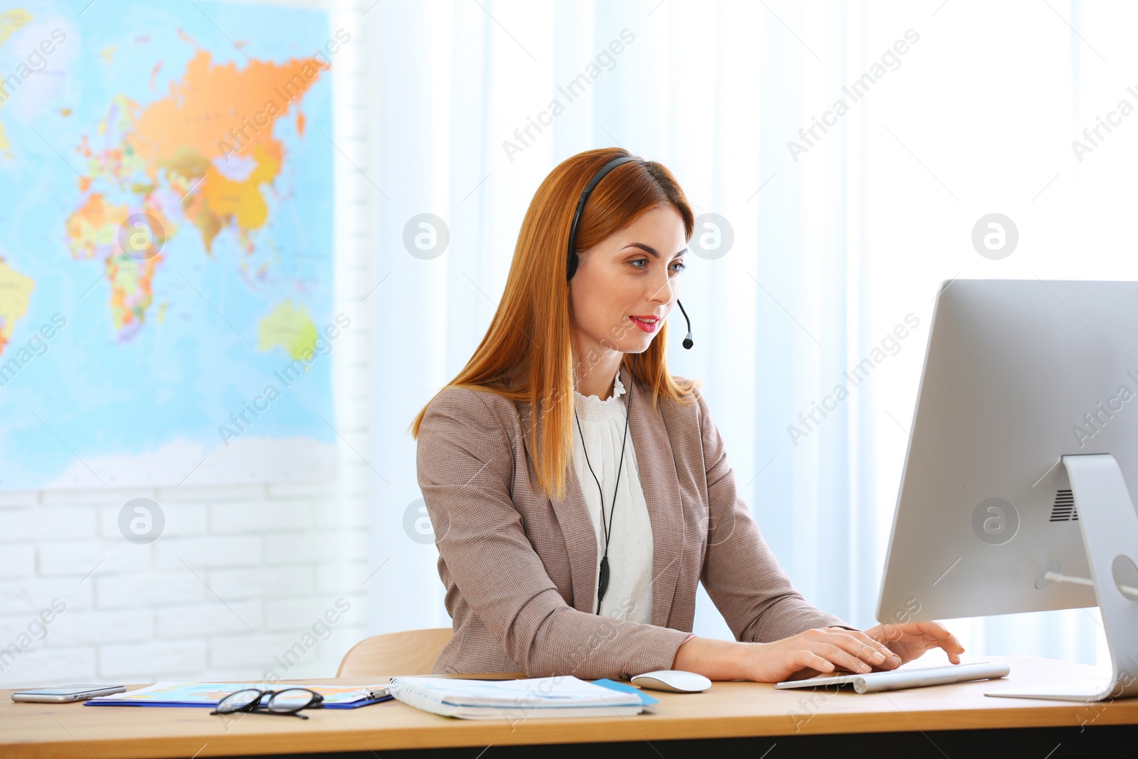 Photo of Beautiful consultant working with computer in travel agency