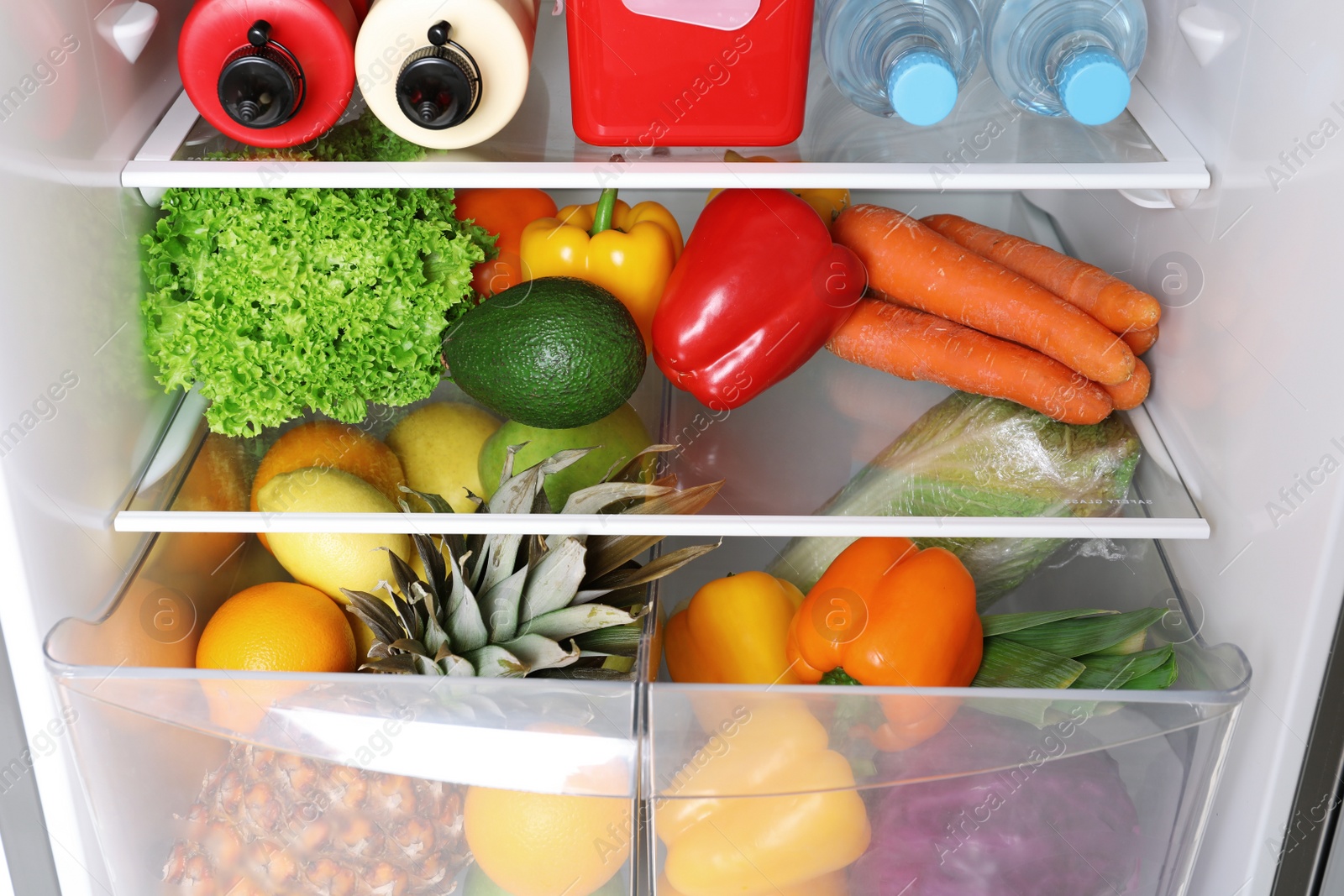 Photo of Open refrigerator with many different products, closeup