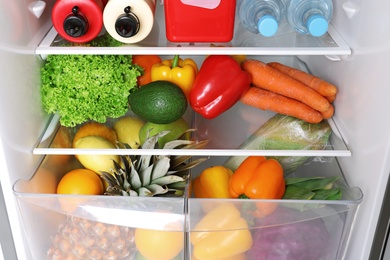 Open refrigerator with many different products, closeup