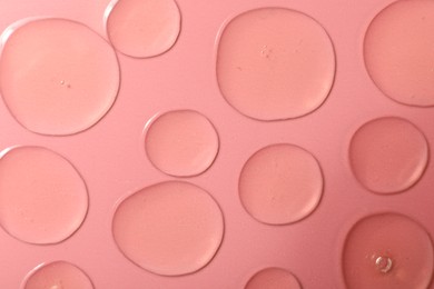 Photo of Drops of hydrophilic oil on pink background, flat lay