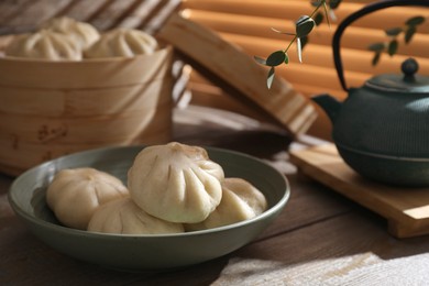 Delicious bao buns (baozi) in bowl on wooden table, closeup