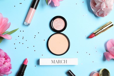 Photo of International Women's day. 8th of March made with powder, makeup products and beautiful flowers on light blue background, flat lay