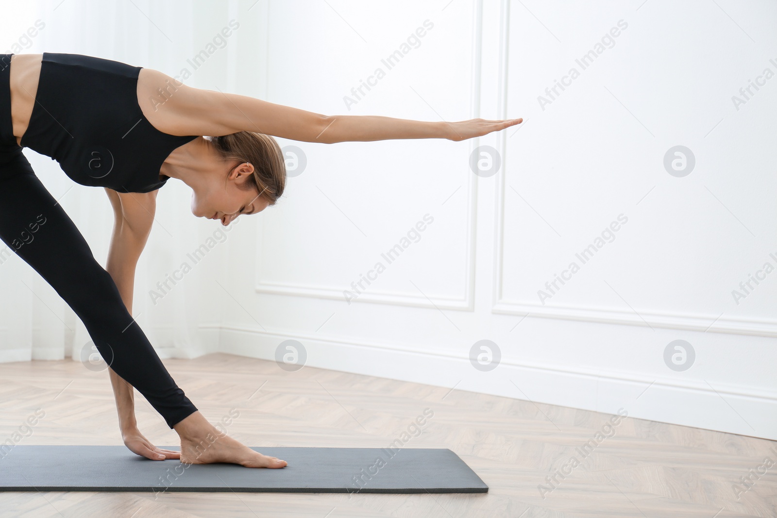 Photo of Young woman practicing triangle asana in yoga studio. Trikonasana pose