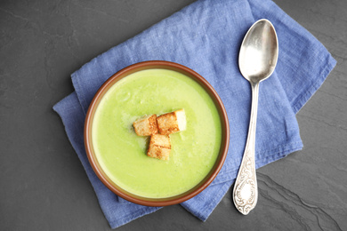 Delicious broccoli cream soup served on dark grey table, top view