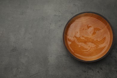 Photo of Wooden bowl with water on grey table, top view. Space for text