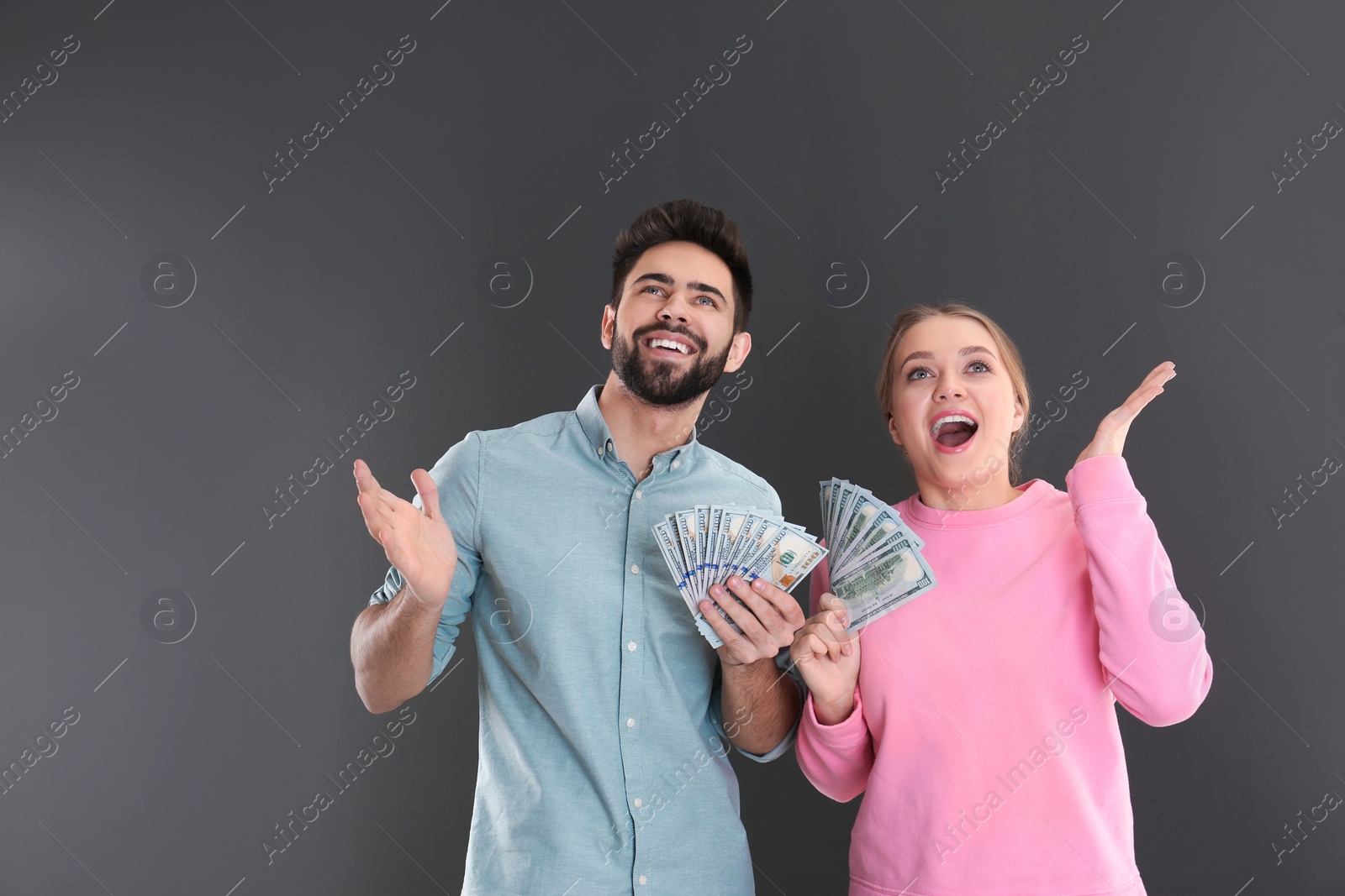 Photo of Happy young couple with money on grey background