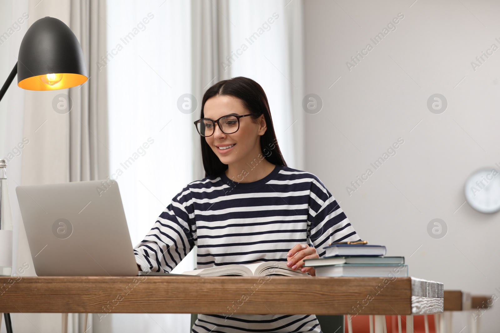 Photo of Young woman with laptop studying at table in library