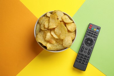 Modern tv remote control and chips on color background, flat lay