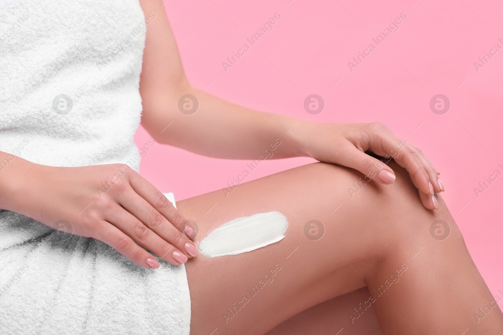 Photo of Woman with smear of body cream on her leg against pink background, closeup