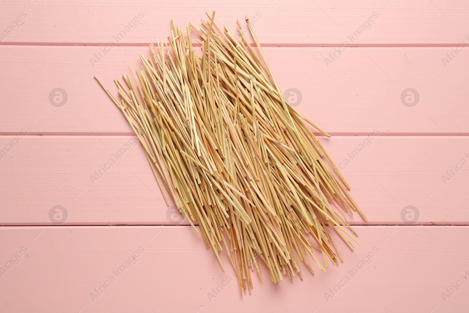 Photo of Heap of dried hay on pink wooden background, flat lay