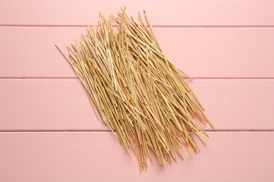 Photo of Heap of dried hay on pink wooden background, flat lay