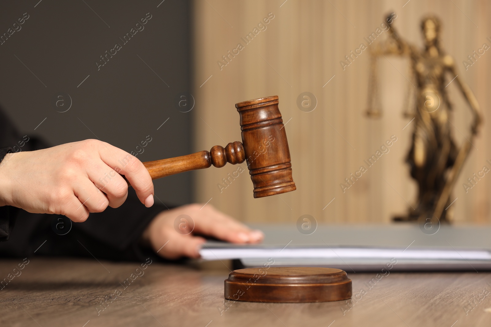 Photo of Judge striking mallet at wooden table in courtroom, closeup. Space for text