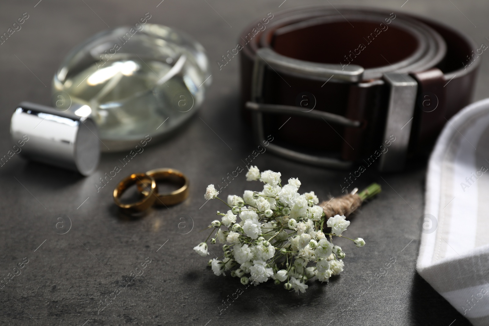 Photo of Wedding stuff. Composition with stylish boutonniere on black table, closeup