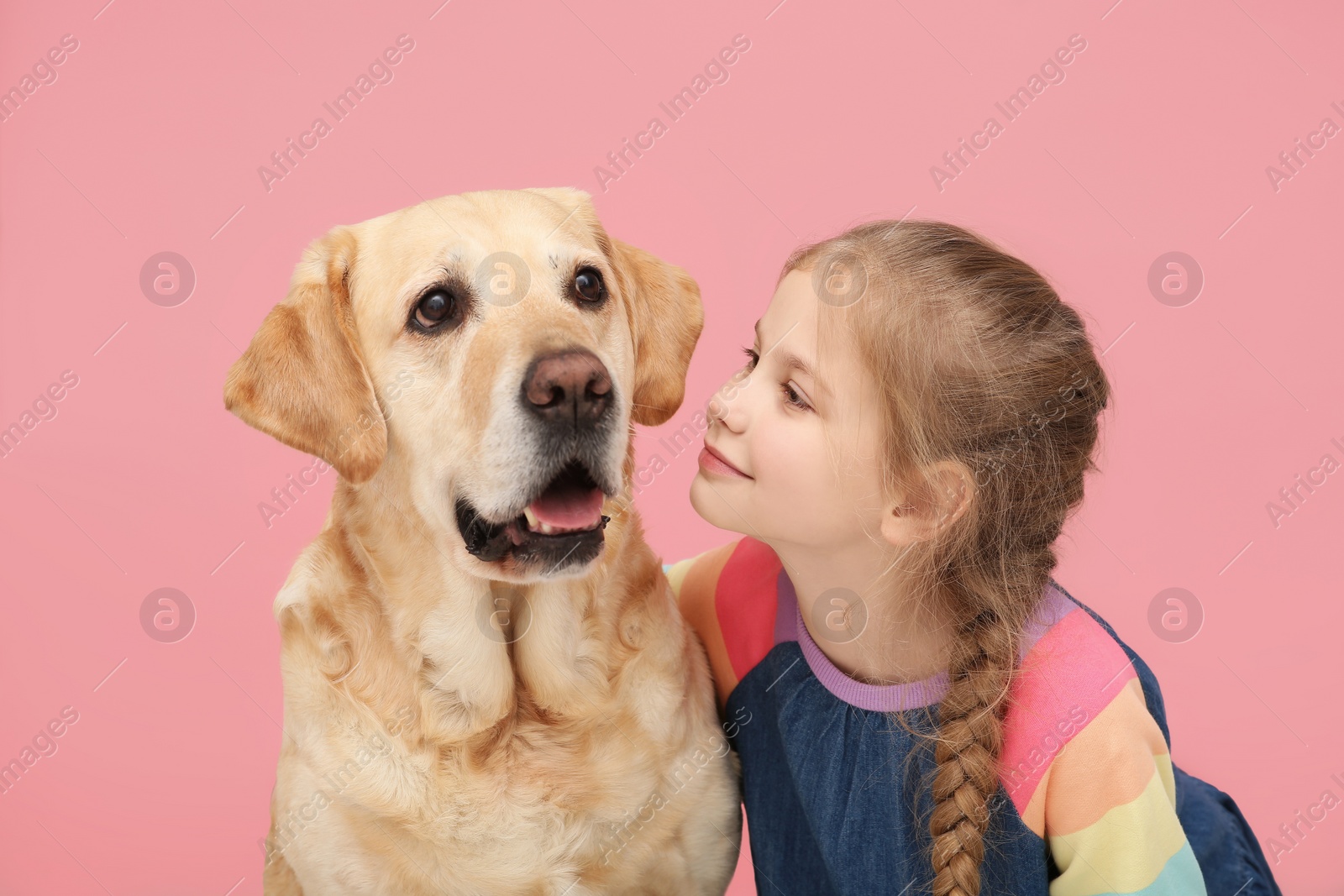 Photo of Young girl with her adorable dog on pink background