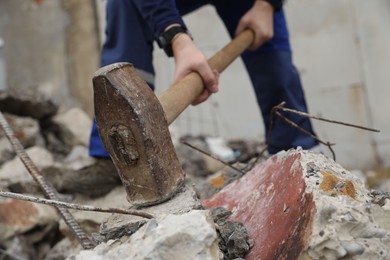 Photo of Man breaking stones with sledgehammer outdoors, selective focus