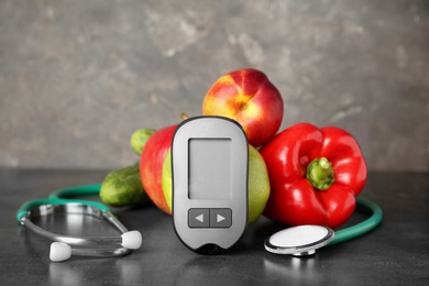 Photo of Digital glucometer, stethoscope, fruits and vegetables on table. Diabetes concept