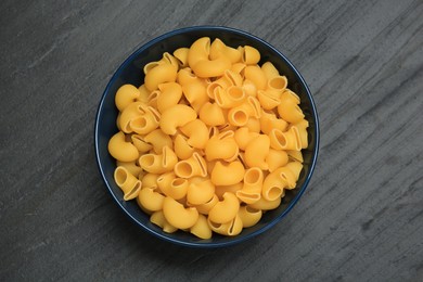 Photo of Raw macaroni pasta in bowl on grey table, top view