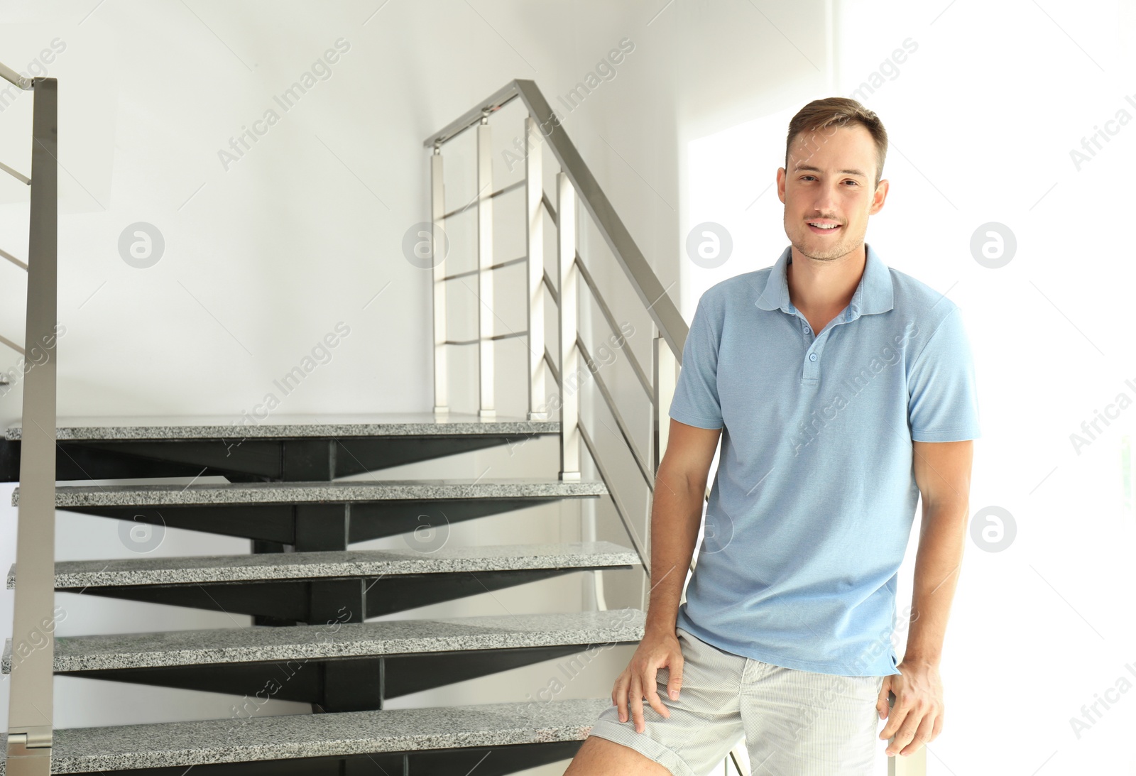 Photo of Young man standing near staircase indoors