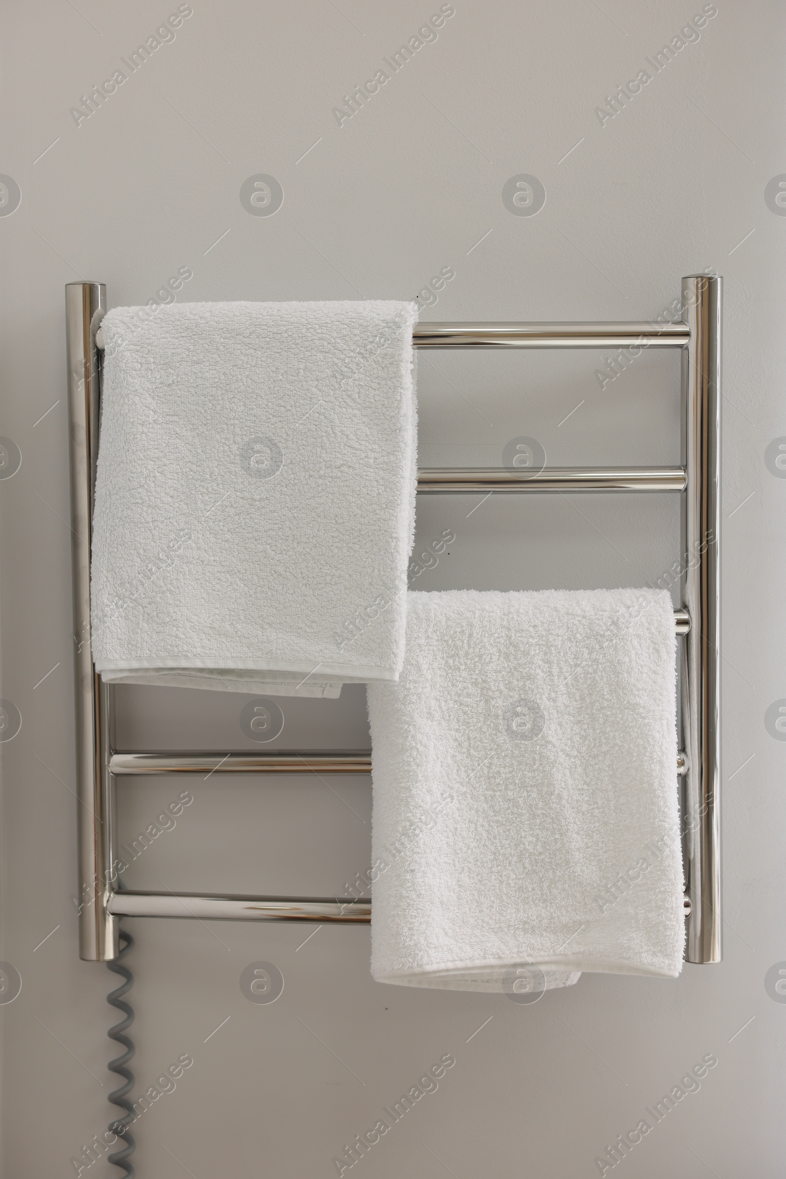 Photo of Heated towel rail with towels in bathroom