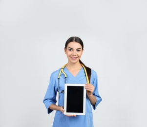 Photo of Portrait of medical assistant with stethoscope and tablet on light background. Space for text