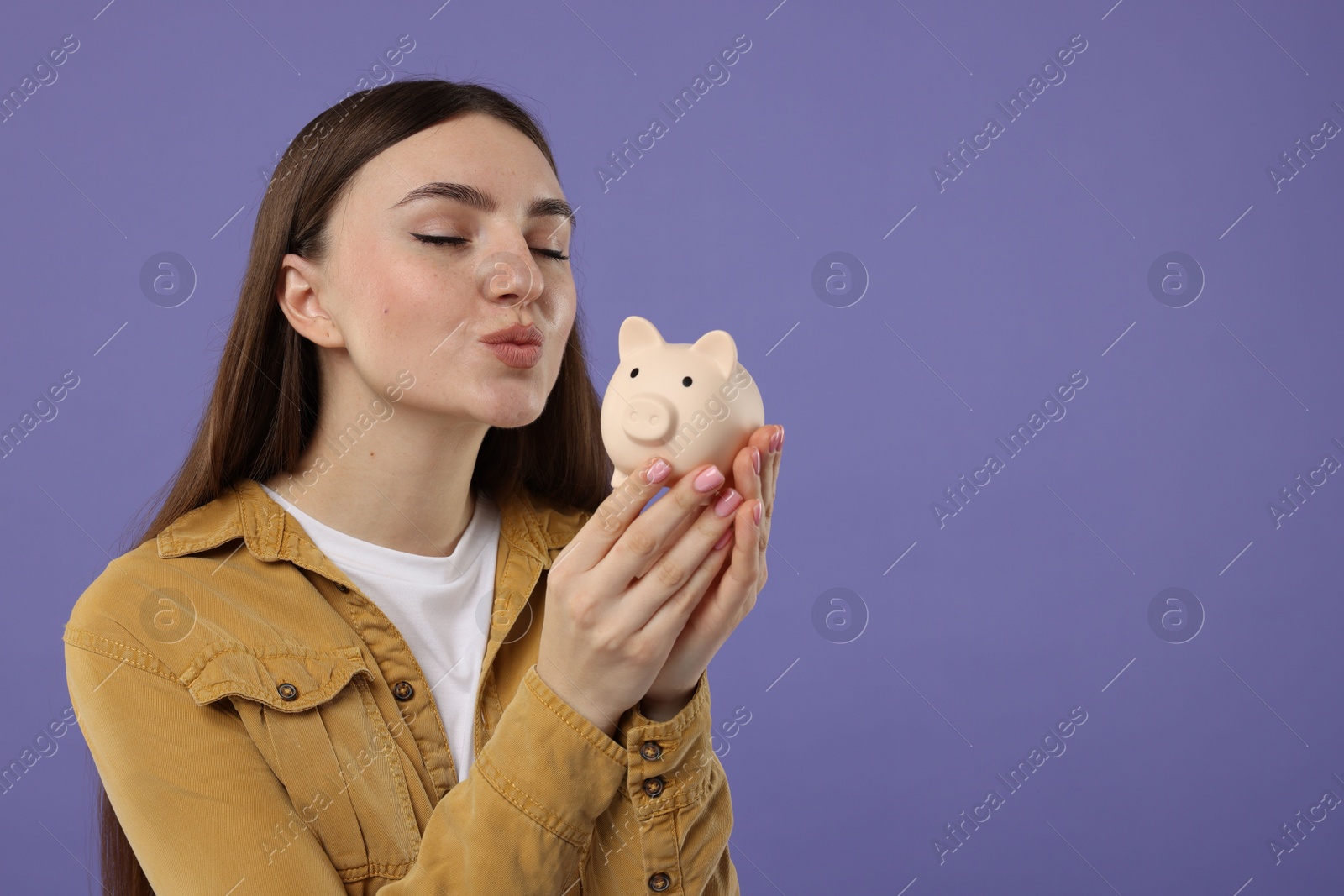 Photo of Woman with piggy bank on purple background, space for text